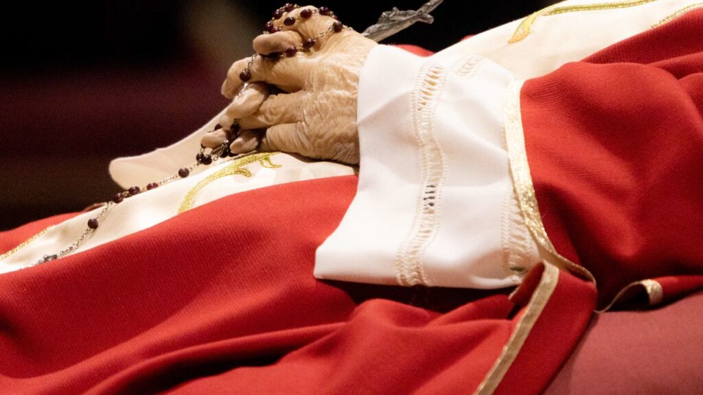 Rosary beads entwined in the hands of the late Pope Emeritus Benedict XVI as his body lies in state on Jan. 3, 2023, in St. Peter's Basilica. | Daniel Ibañez/CNA