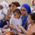 A nun of the Incarnate Word sits with children during Sunday morning Mass at the Church of the Holy Family in Gaza City on July 20, 2025. (photo: OMAR AL-QATTAA / AFP via Getty Images)