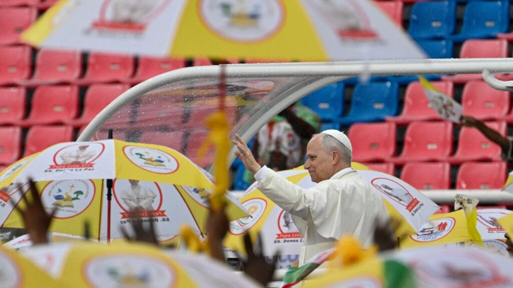 Pope Leo XIV greets a crowd under umbrellas during a meeting with families at Bata Stadium in Equatorial Guinea, Wednesday, April 22, 2026. | Credit: Vatican Media