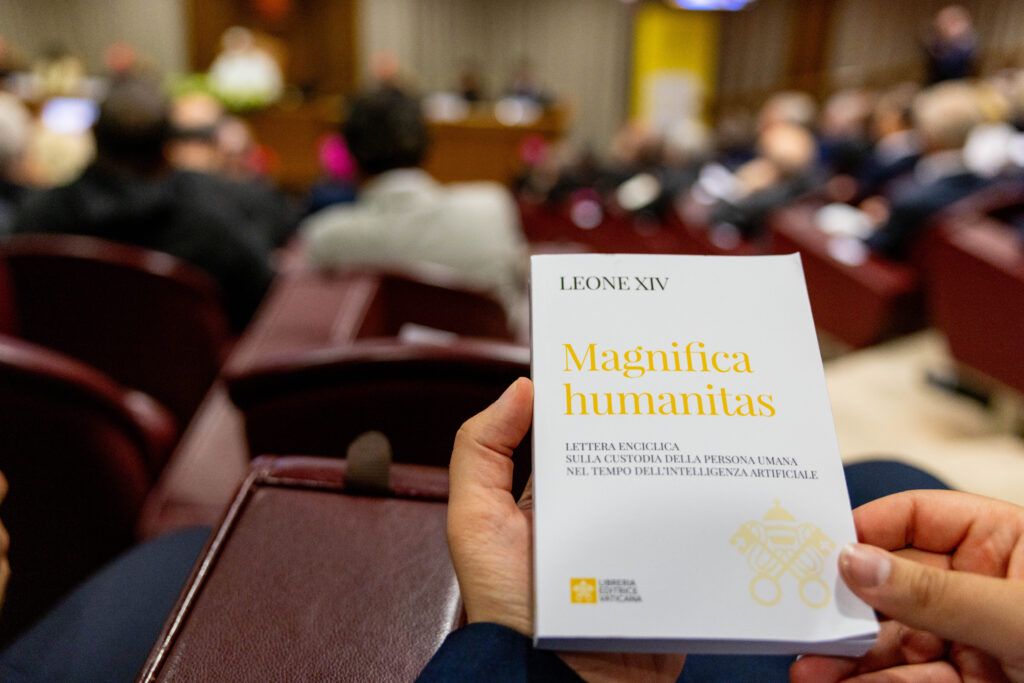 A hard copy of Magnifica Humanitas, Pope Leo XIV’s first encyclical, is held by an attendee at the document’s presentation on May 26, 2026, in the New Synod Hall at the Vatican. | Credit: Daniel Ibanez/EWTN News