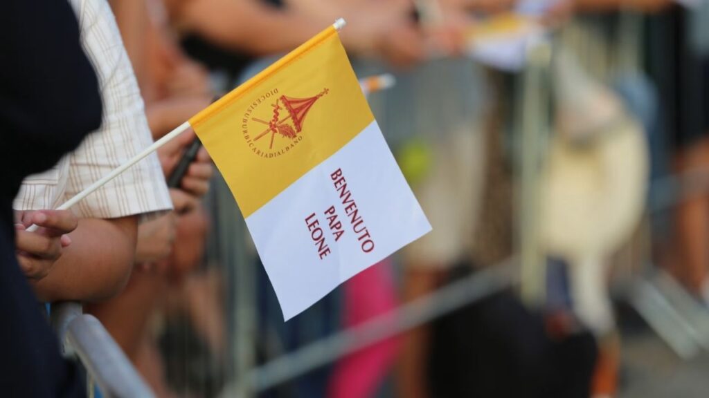 A pilgrim waves a flag welcoming Pope Leo XIV to Lake Albano at Castel Gandolfo, Aug. 29, 2026. Leo took part in a Marian procession on the lake, becoming the first pope to travel by boat across the waters there according to the Vatican. | Credit: Zofia Czubak/EWTN News