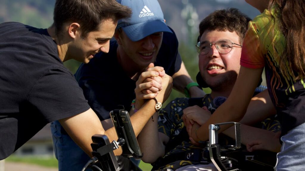 Giacomo Mattivi, a young Italian man with Duchenne muscular dystrophy, is surrounded by friends in a still from the film “Green Lava.” | Credit: Photo courtesy of “Green Lava”