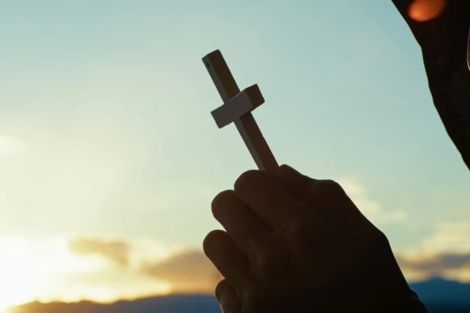 Stock image of a young man holding a crucifix. | Credit: Francesco Sgura/Shutterstock