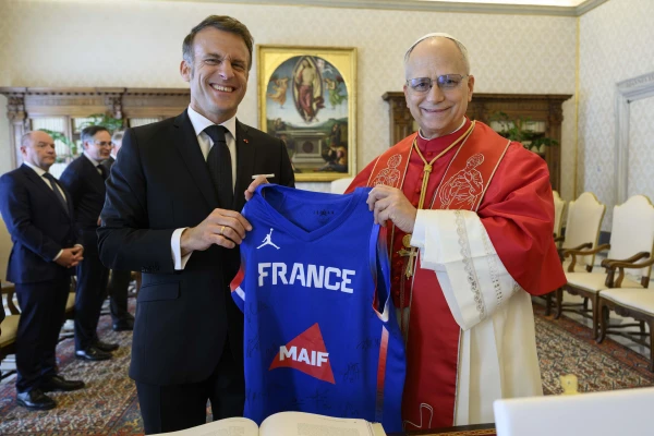 French President Emmanuel Macron presents Pope Leo XIV with a French national basketball team jersey during an audience on April 10, 2026, at the Vatican. | Credit: Vatican Media