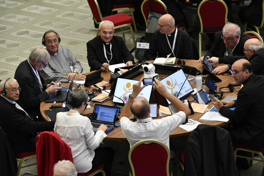 Synod delegates, including Archbishop Filippo Iannone, center, sit in a small group in the Paul VI Hall during the Synod on Synodality’s first monthlong meeting in October 2023. | Credit: Vatican Media